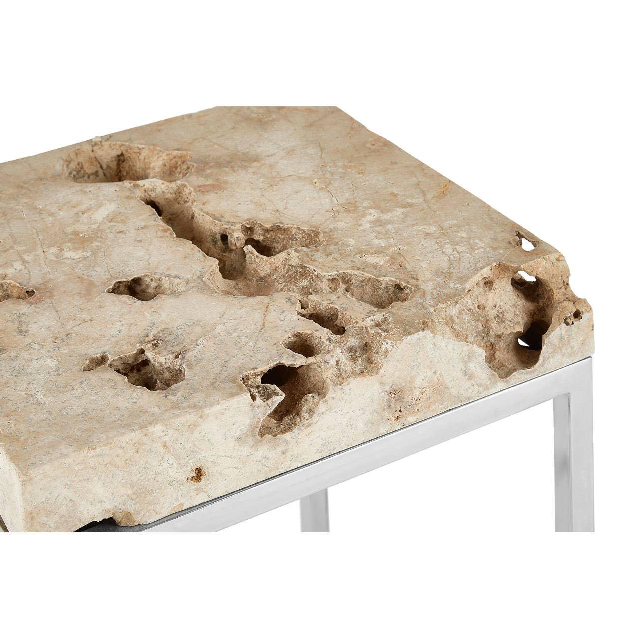 Travertine stone coffee table with raw edge and chrome metal leg, close-up corner view