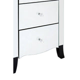 White chest of drawers featuring five spacious drawers with sleek silver knobs, a curved bottom edge, and elegant black legs. The design includes a mirror frame that enhances its modern aesthetic