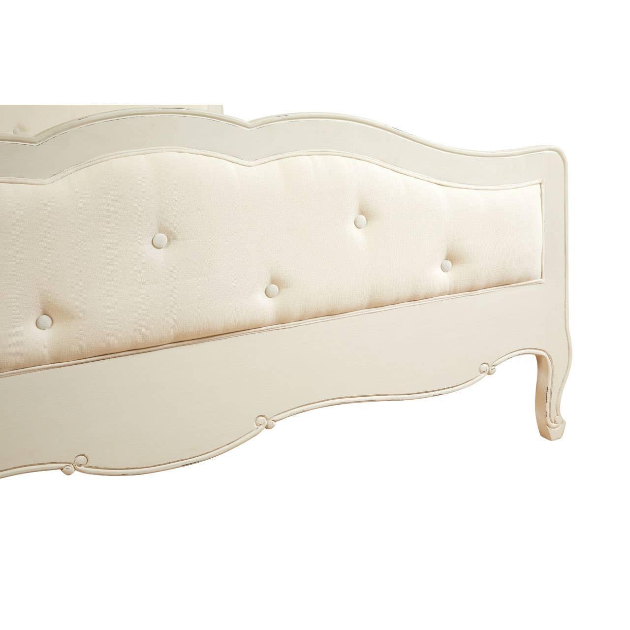 Cream upholstered bed frame with button detailing and curved wooden footboard