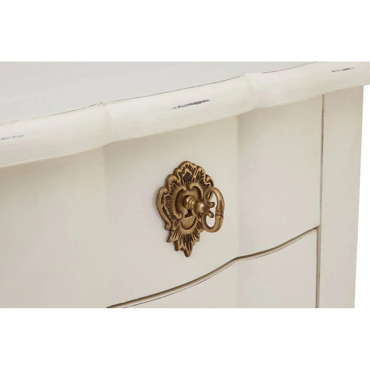 Close view of cream drawer with ornate brass handle and distressed paint finish
