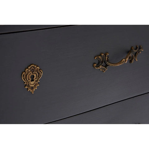Close-up of black chest of drawers with ornate brass handle and keyhole
