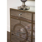 Champagne gold and mirrored sideboard featuring a sleek design with a single drawer and decorative circular detailing on the front, complemented by a polished surface and a stylish lamp on top. The sideboard is set against a wooden floor, enhancing its elegant appearance