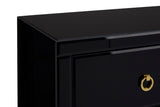 Black cabinet with a sleek, modern design featuring a smooth top surface and a single drawer with a circular gold handle. The cabinet has clean lines and a glossy finish, emphasizing its contemporary aesthetic