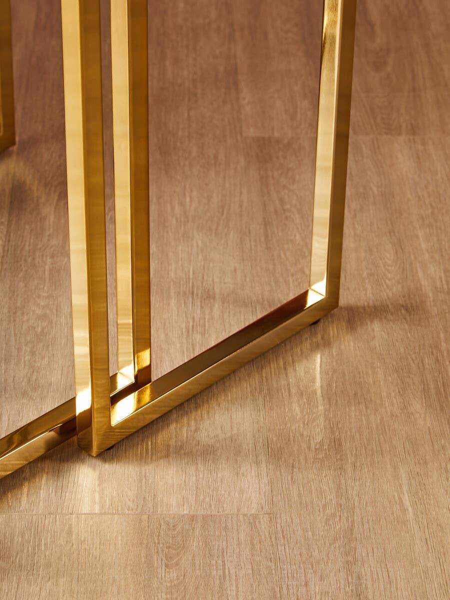 Gold metal table legs on light wood flooring, modern furniture detail