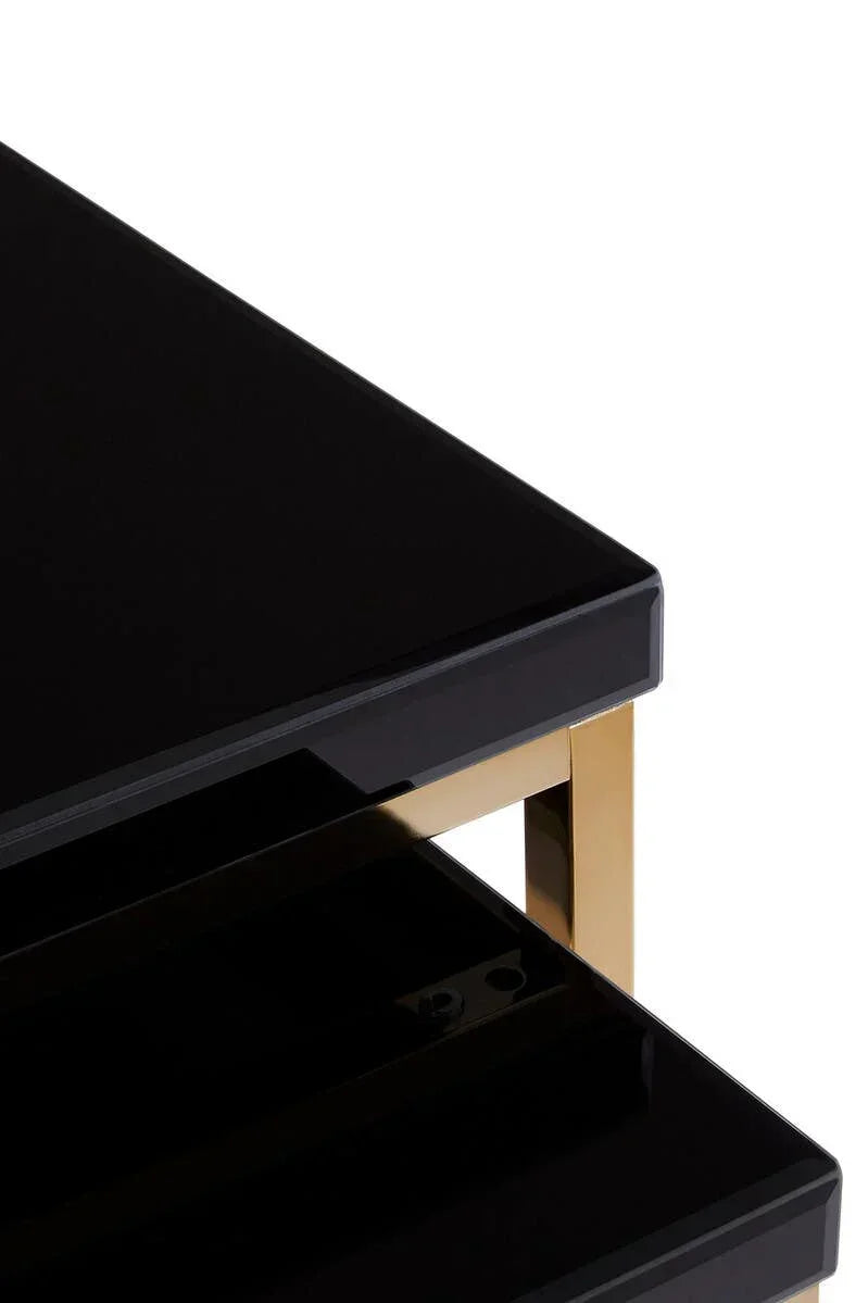Black glass coffee table with gold metal frame, close-up of stacked tabletop corners
