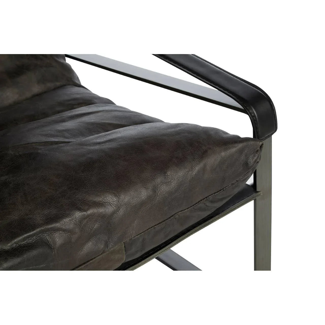 Close-up of brown leather armchair cushion and black metal armrest detail