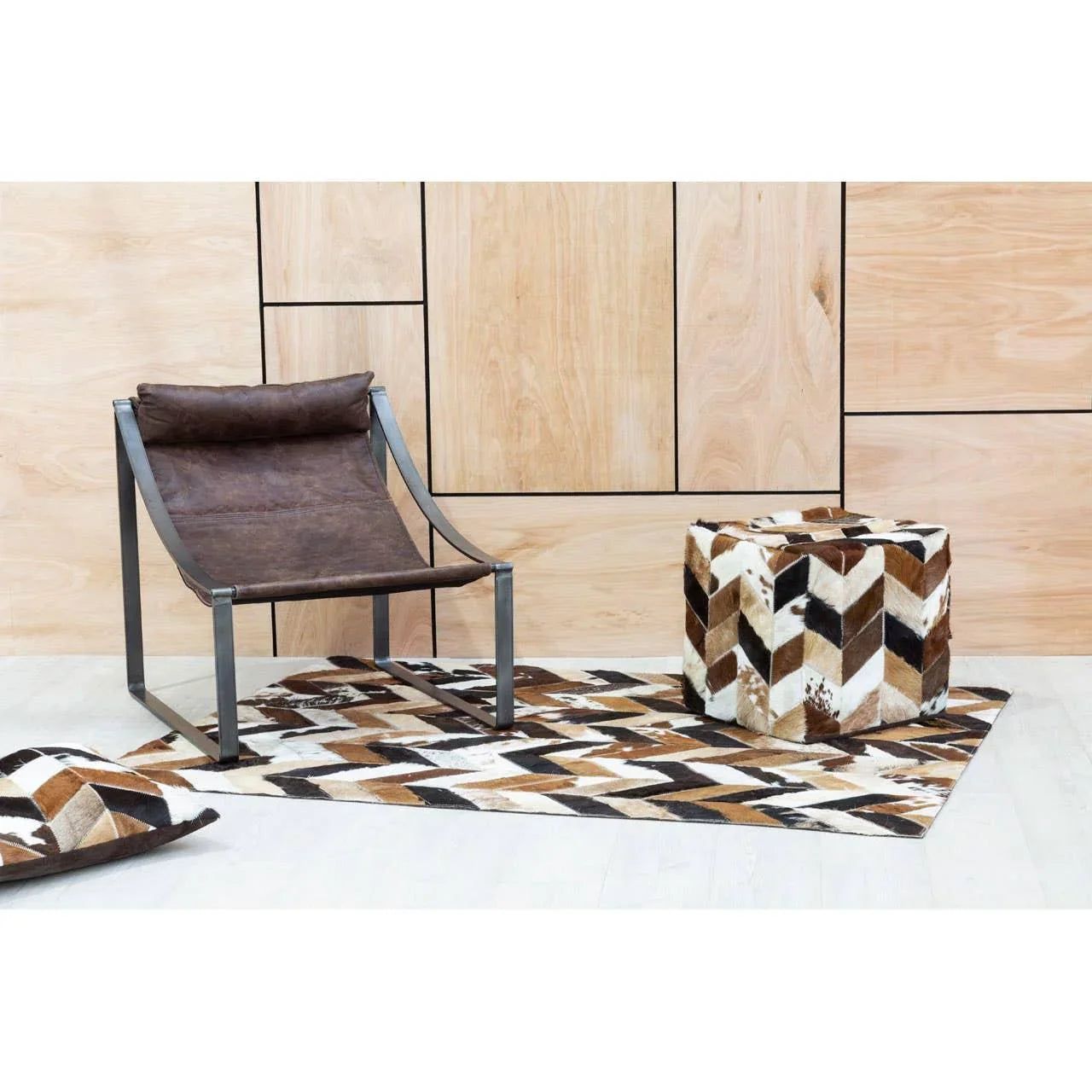 Brown leather accent chair with metal frame beside patterned cube ottoman and rug