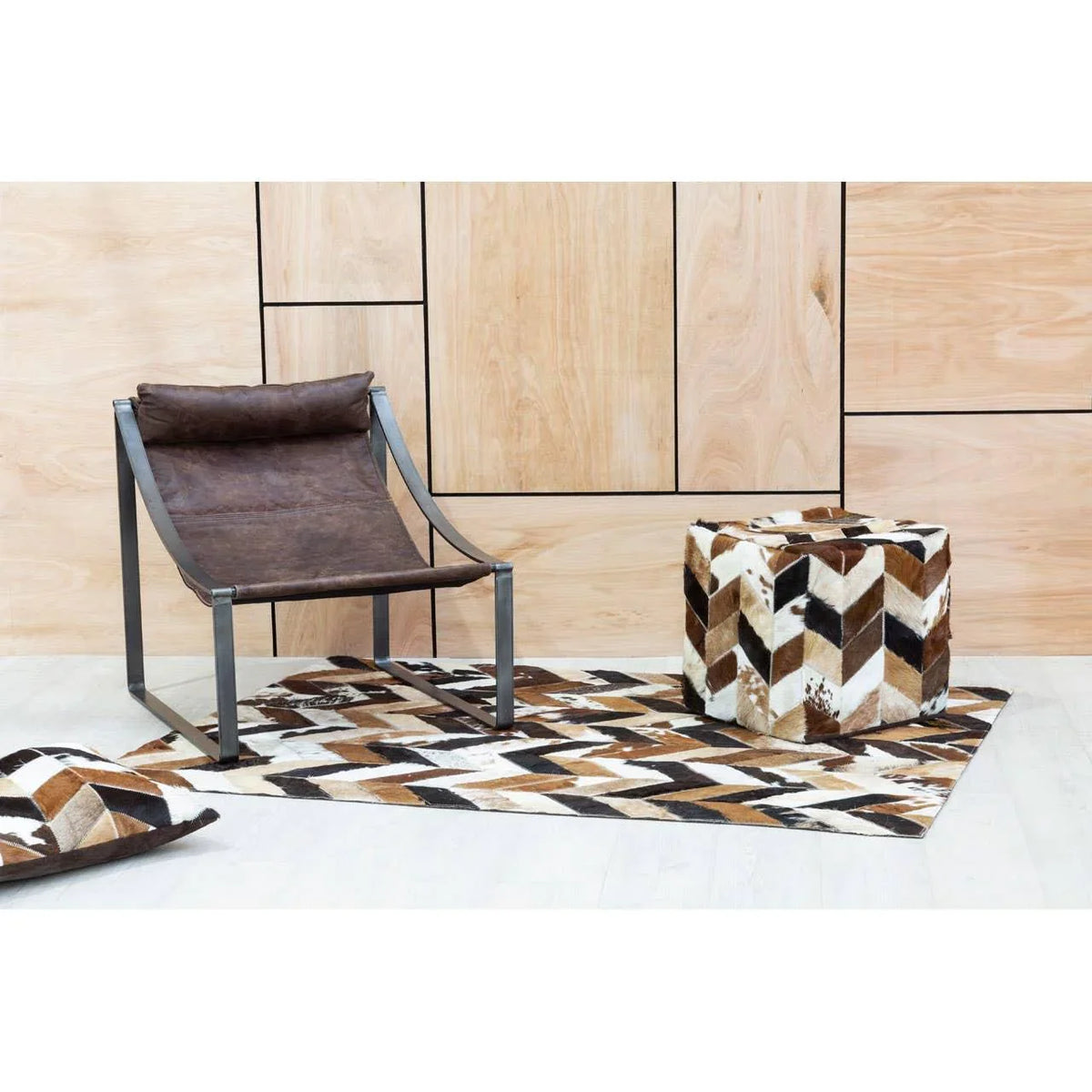 Brown leather accent chair with metal frame beside patterned cube ottoman and rug