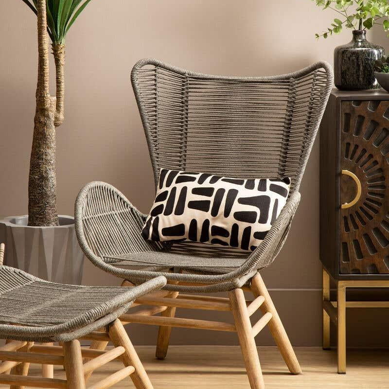 Modern rattan accent chair with matching footstool and geometric cushion in living room