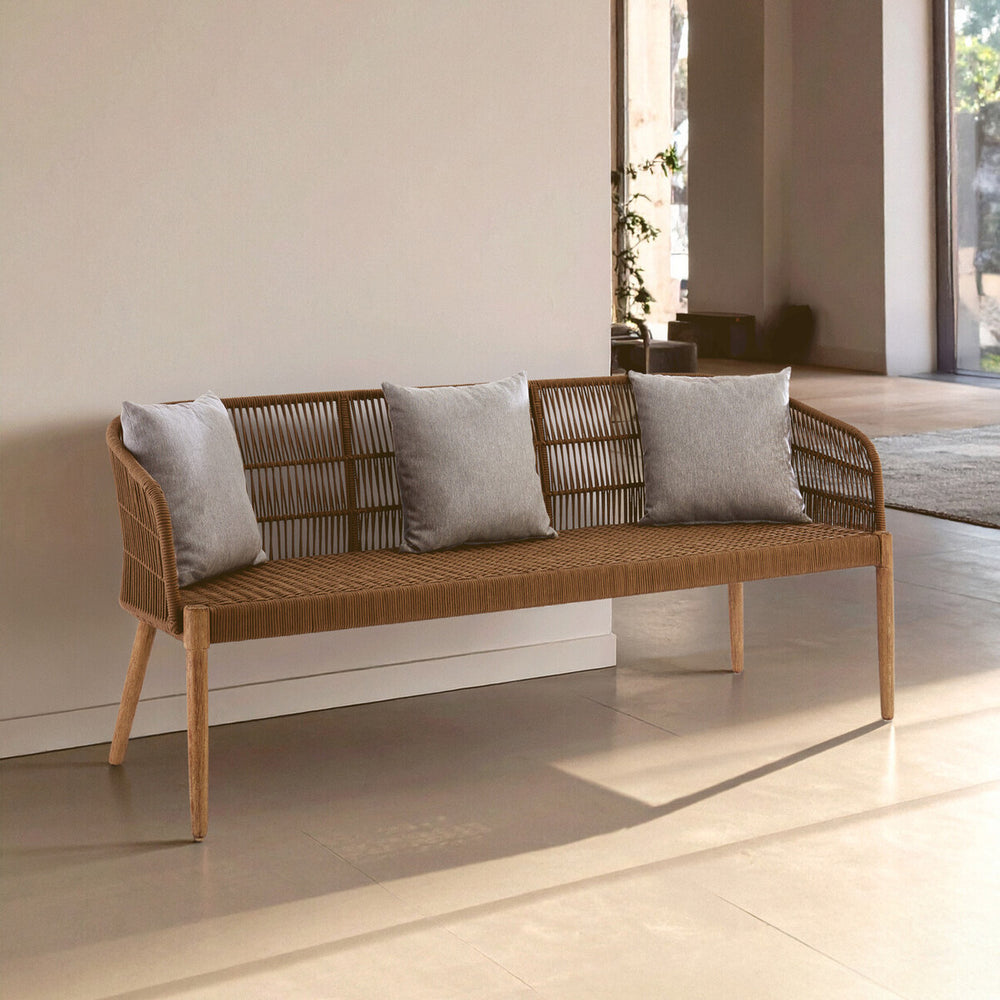 A three-seater sofa featuring a woven rope design with a wooden frame and legs. The sofa is adorned with three light gray cushions, positioned against a neutral wall in a bright, airy room with natural light streaming in. The floor is a light-colored material, enhancing the modern aesthetic of the space