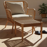 Woven rope footstool in a natural finish, placed next to a light-colored armchair with a beige cushion. The footstool features a square design with a textured surface, and the scene is illuminated by soft, natural light, highlighting the wooden floor and a small potted plant in the background. A pair of dark slippers is positioned beside the footstool