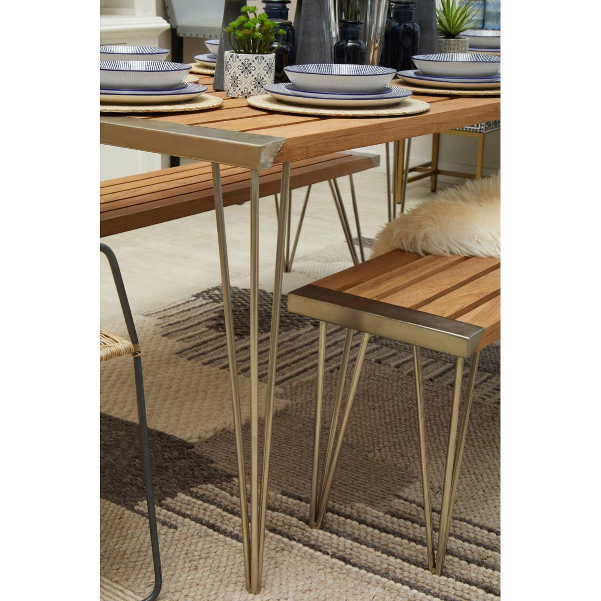 Wooden dining table and bench with metal legs set for four on patterned rug