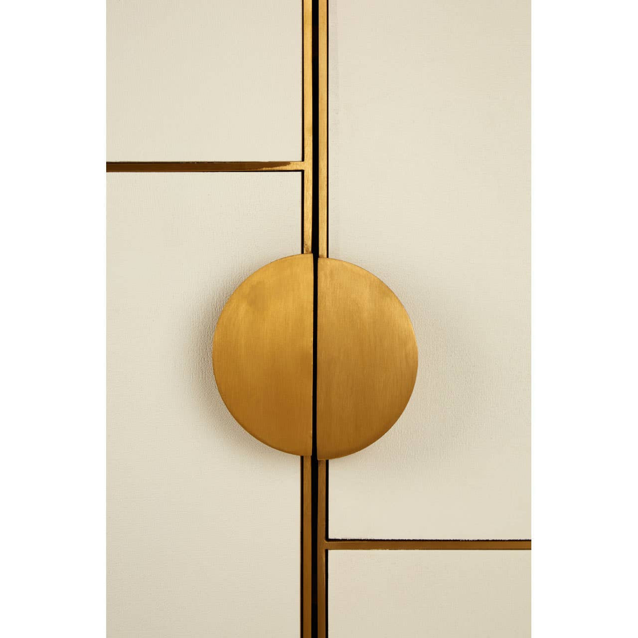 Close-up view of a cabinet featuring a smooth oak wood finish and brushed gold accents. The cabinet door has a round gold handle positioned centrally, with a geometric design visible on the surface. The overall color scheme combines warm wood tones with elegant gold elements