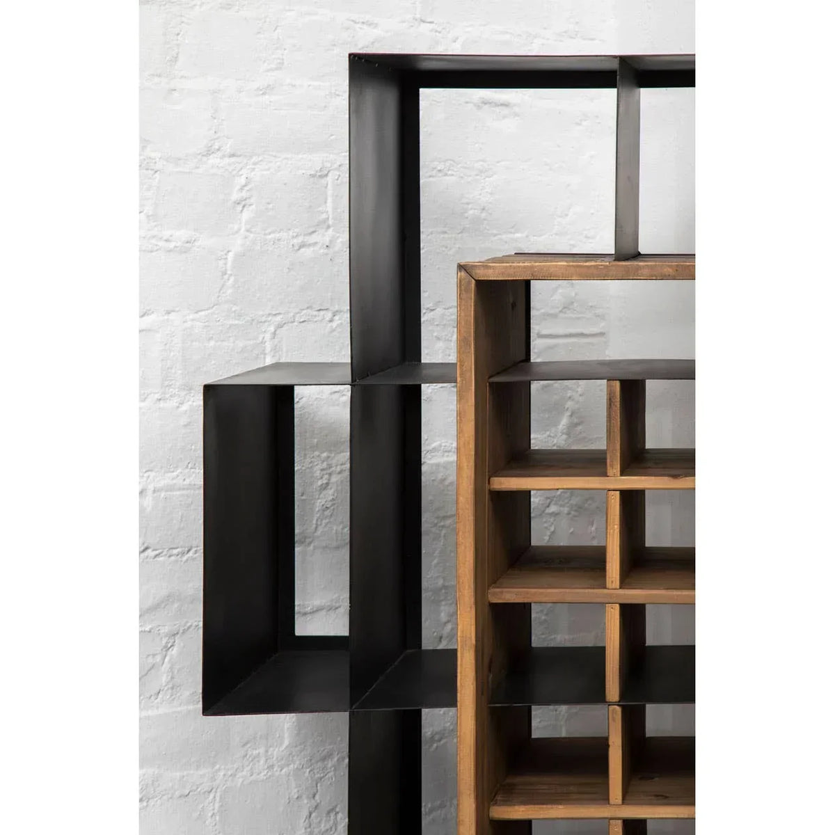 Black metal and wood shelving unit with grid and open cube sections against white wall