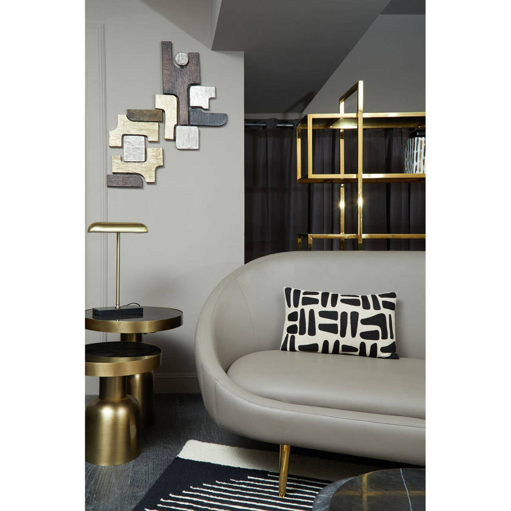 Brown leather effect 3 seater sofa with sleek lines and a modern design, positioned in a stylish living room setting. The sofa is complemented by decorative pillows and surrounded by contemporary furniture, including a gold accent table and geometric wall art. The overall color palette features neutral tones with metallic accents
