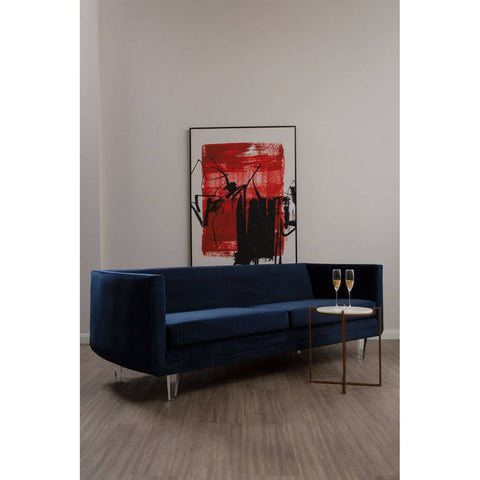 Navy velvet three-seater sofa with a sleek design, featuring a low backrest and a side table integrated into the armrest, set against a neutral wall with a bold red and black artwork in the background. The sofa is supported by slender gold legs, and the floor is made of light wood