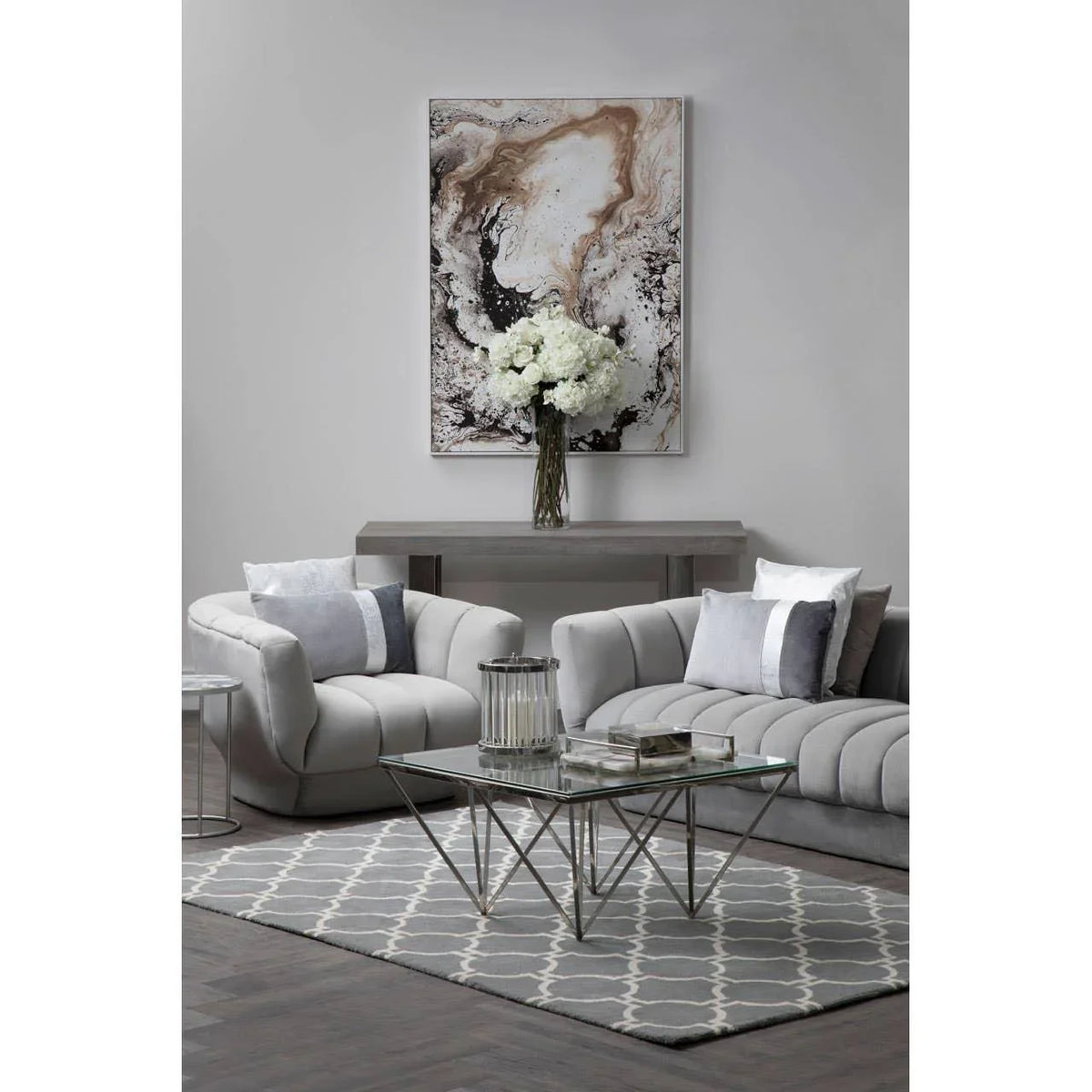 Grey velvet sofa set with glass coffee table and geometric rug in modern living room