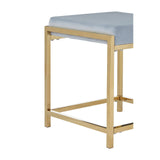 Powder blue velvet stool with a gold metal frame, featuring a square top and a minimalist design. The legs are straight and provide a sturdy base, highlighting a modern aesthetic