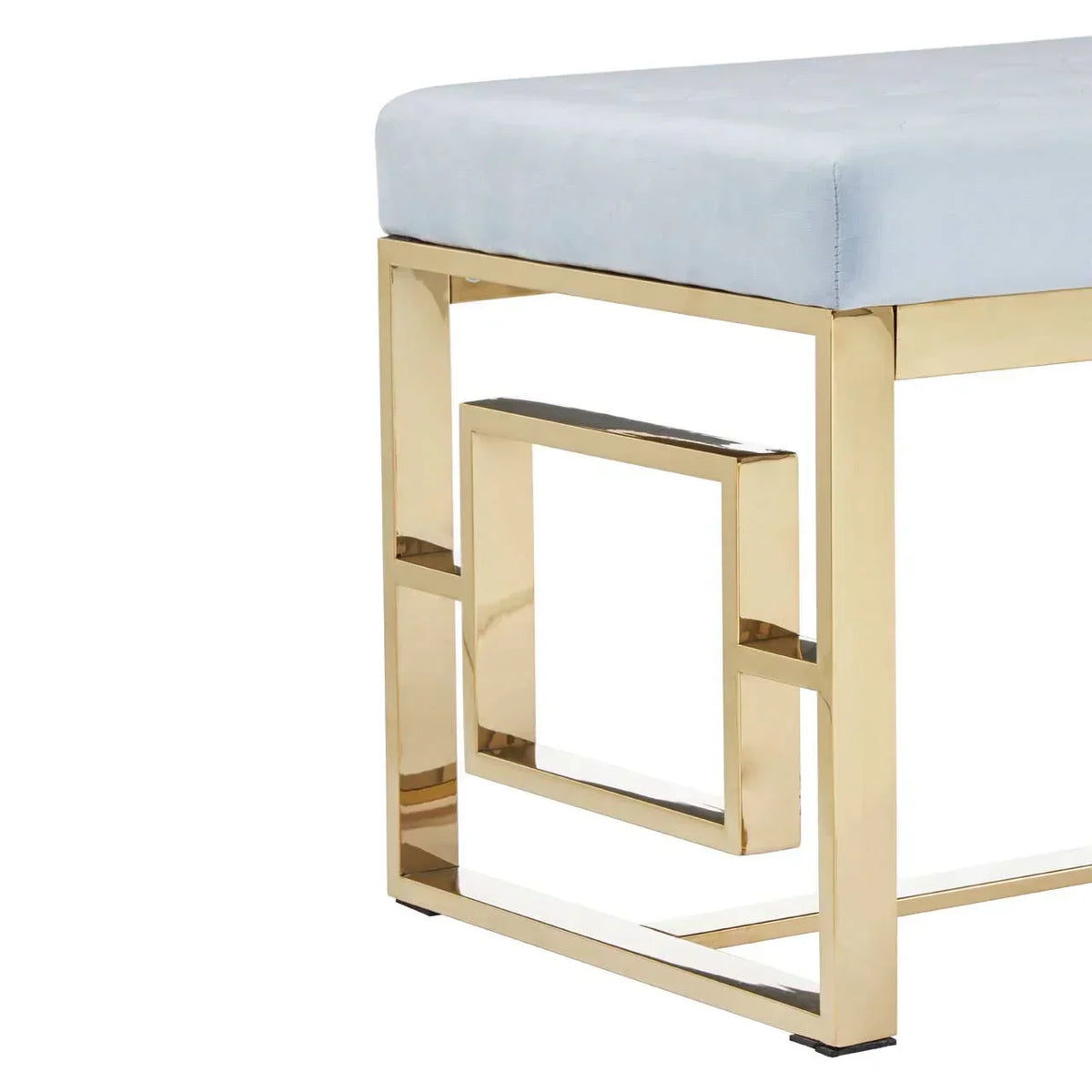 Upholstered bench with gold metal geometric legs and light blue cushioned seat, side view