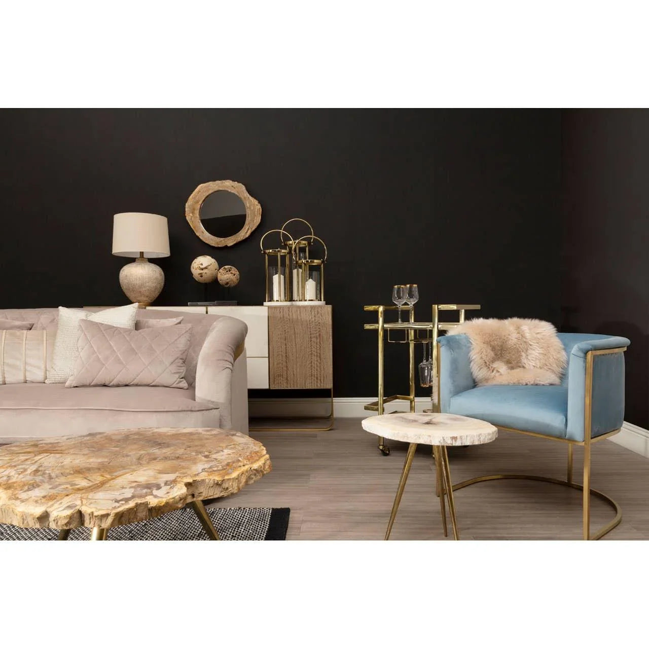 Modern living room with beige sofa, blue accent chair, gold bar cart and stone coffee tables