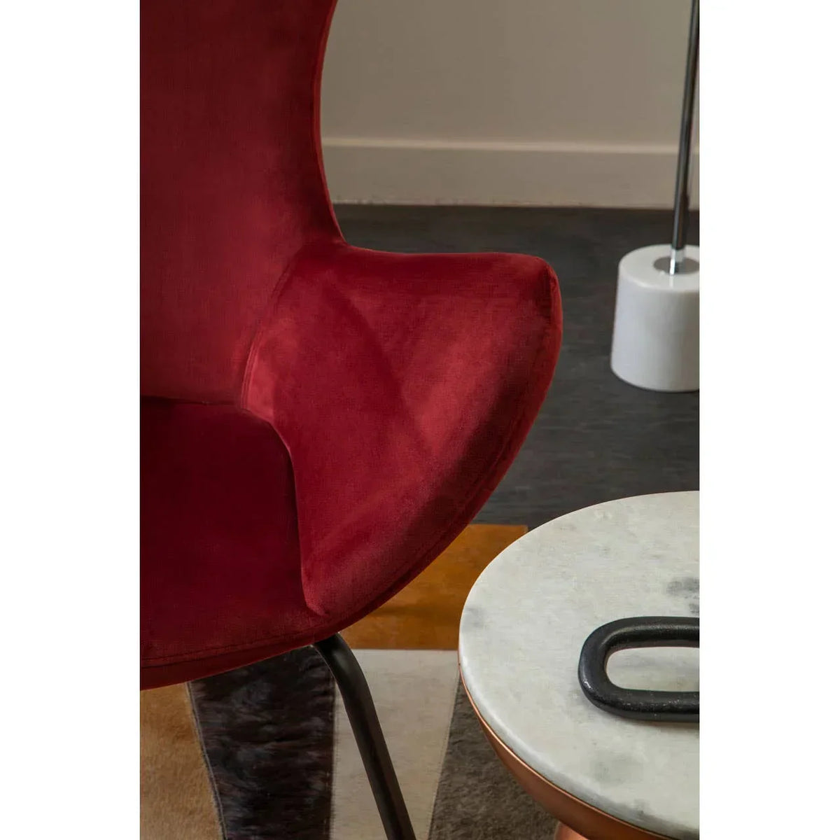 Red velvet accent chair beside round marble coffee table with modern decor