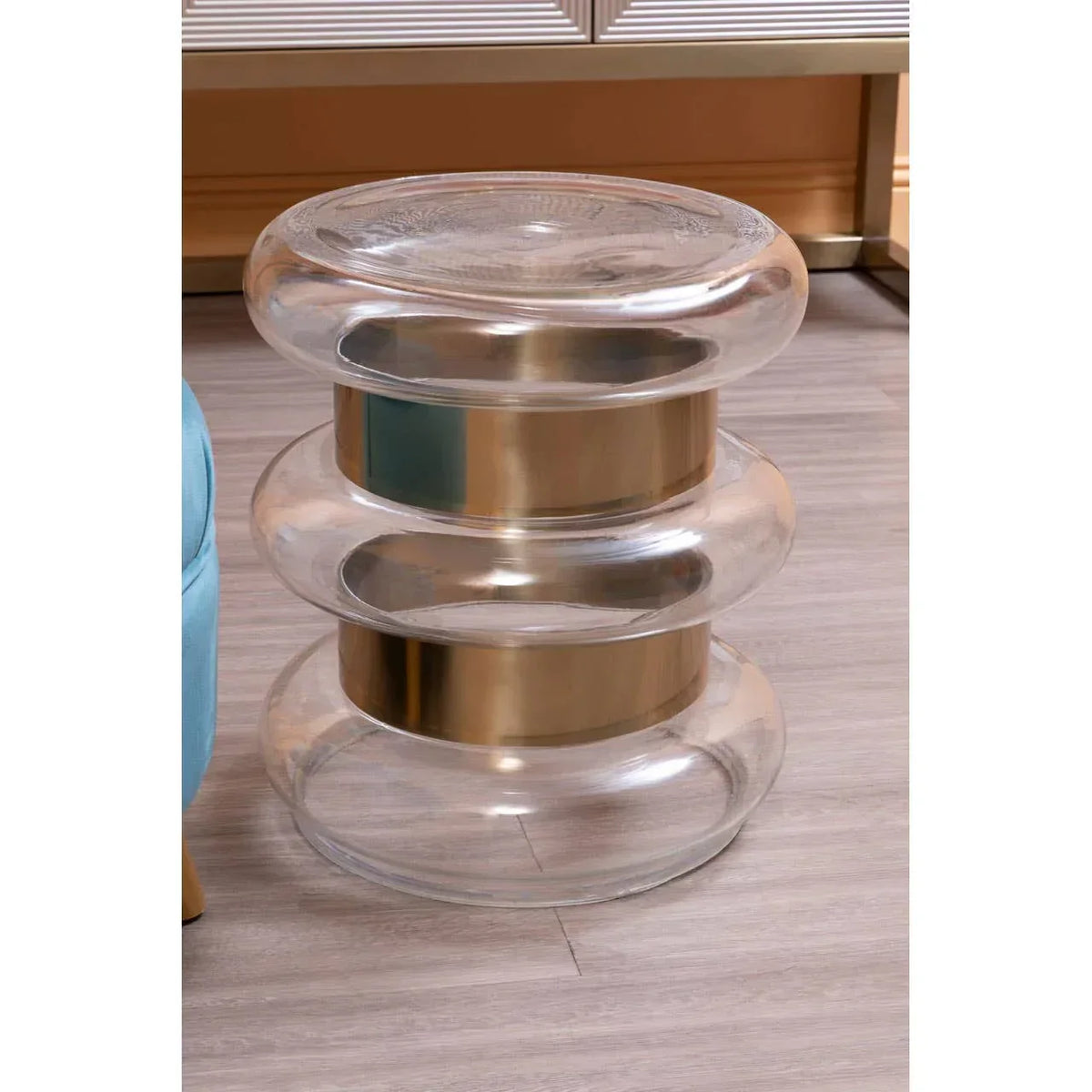 Modern glass side table with gold metallic bands on light wood floor