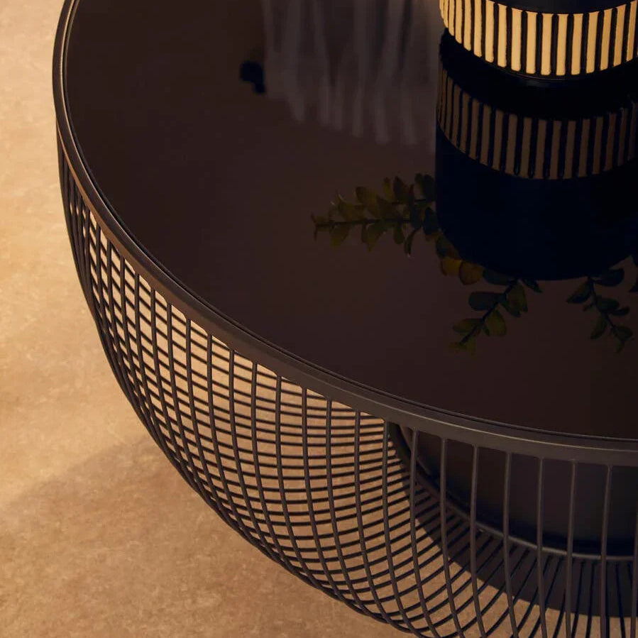 Round black wire frame coffee table with glass top and decorative vase detail