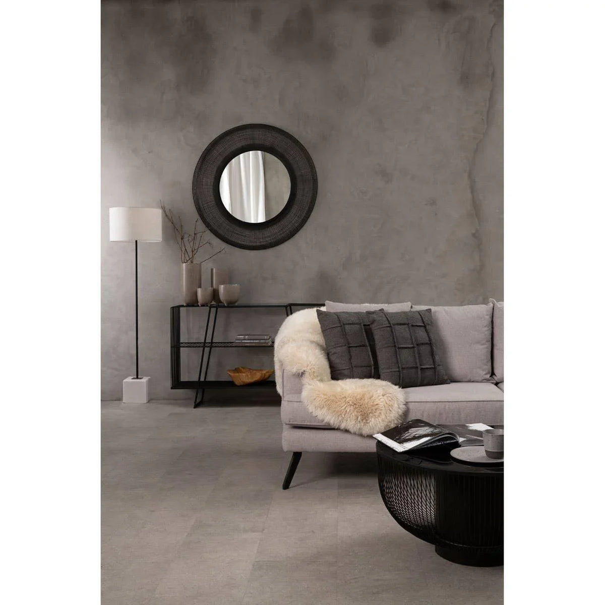 Modern grey sofa with black cushions and sheepskin throw in minimalist living room