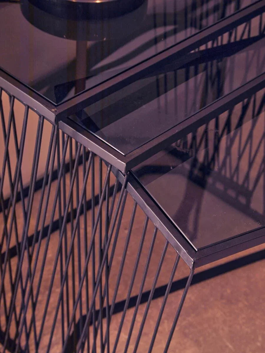 Modern black metal console table with glass top and geometric frame, angled side view