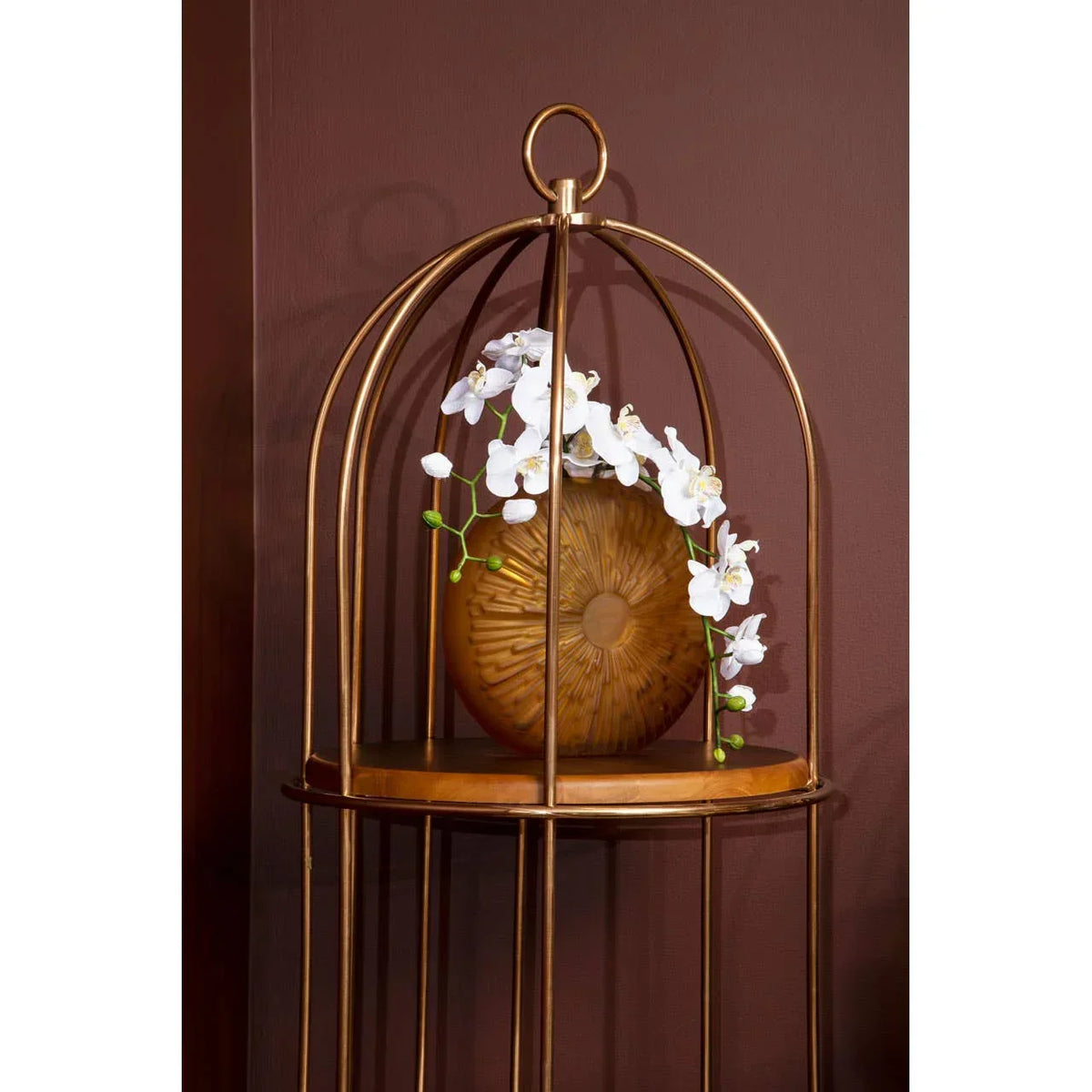 Gold accent table with decorative brown vase and white artificial orchids on display shelf