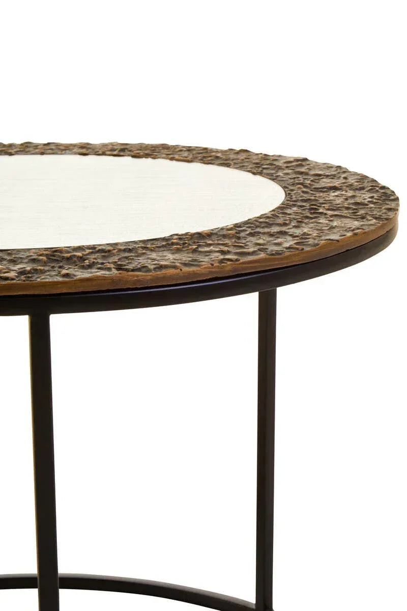 Round metal side table with textured bronze edge and glass top, angled close-up view