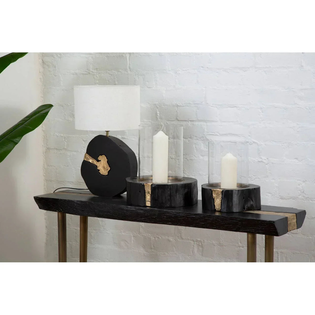 Black wood console table with gold accents, lamp, and two pillar candle holders