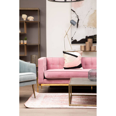 A stylish three-seat sofa in a soft pink fabric, featuring a modern design with gold legs. The sofa is adorned with a decorative black and pink pillow, positioned on a light-colored rug. In the background, there is a minimalist bookshelf and abstract wall art, creating a contemporary living space