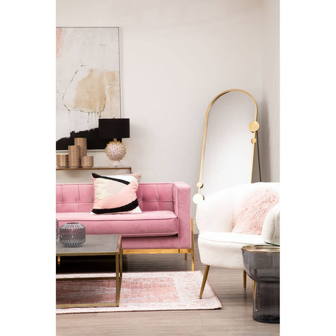 A stylish three-seat sofa in a soft pink fabric, featuring gold metal legs and a modern design. The sofa is adorned with decorative pillows and is positioned in a bright, contemporary living room setting, alongside a white accent chair and a large mirror. A light-colored rug and wall art complete the cozy atmosphere