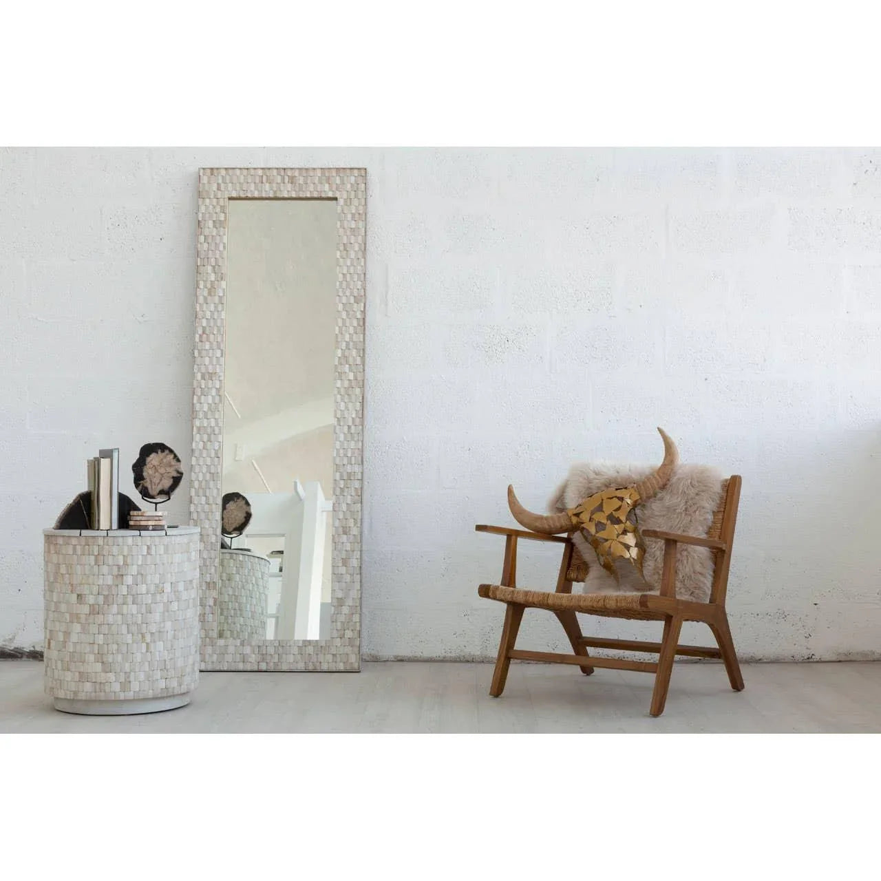 Tall rectangular wall mirror with mosaic frame beside wooden accent chair and round side table