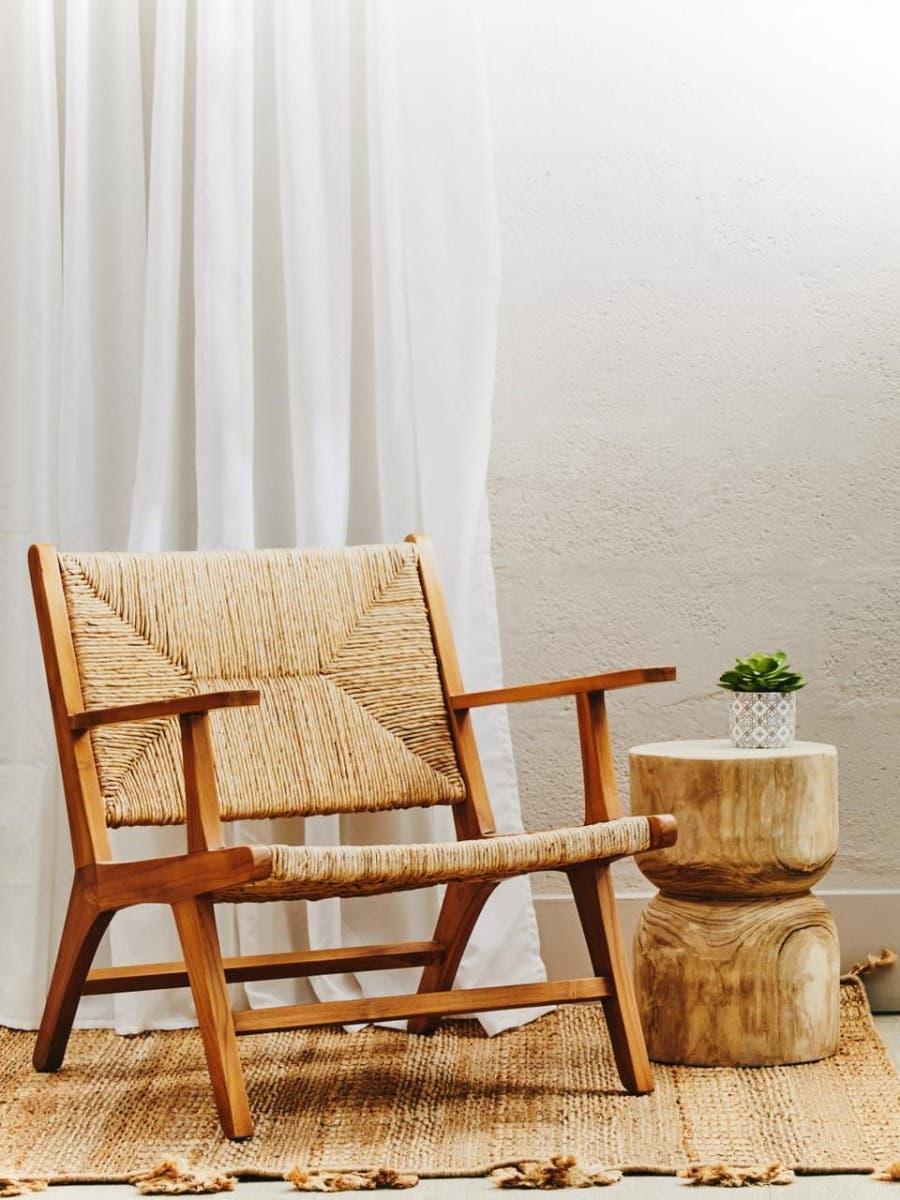 Wooden accent chair with woven seat beside natural wood side table on jute rug