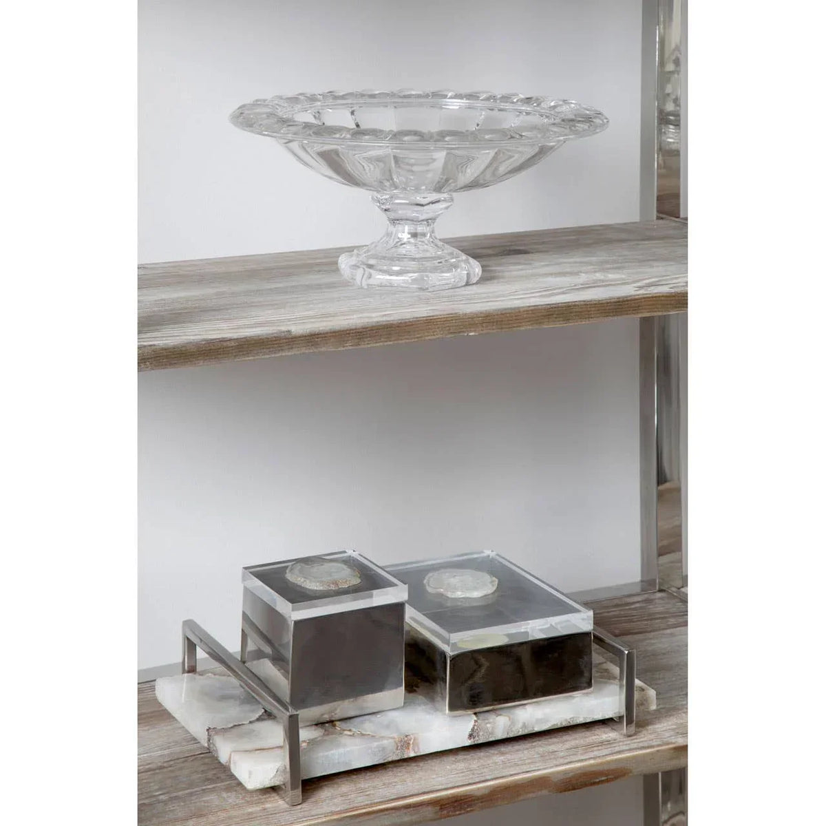 Clear glass pedestal bowl and two marble storage boxes on rustic wooden shelving unit