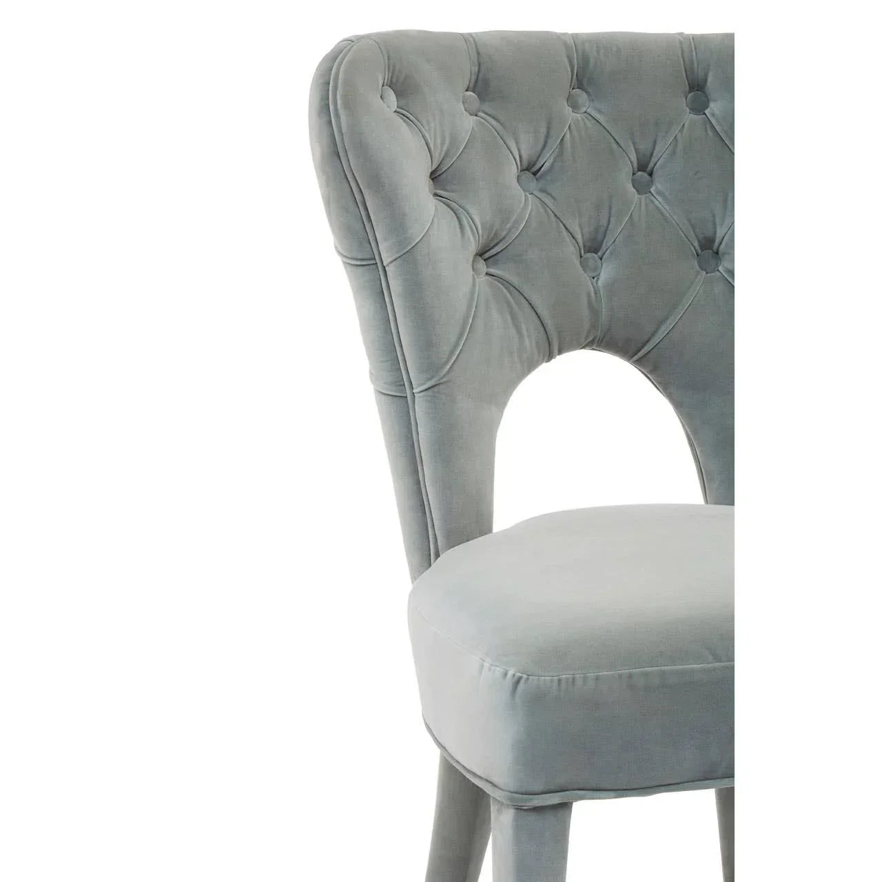 Light grey velvet dining chair with tufted backrest and cut-out detail, side angle closeup