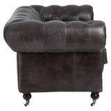 Dark grey brown leather Chesterfield 2 seat sofa featuring a tufted backrest and rolled arms, supported by wooden legs with casters for mobility. The upholstery has a rich texture, highlighting the classic design elements of the sofa
