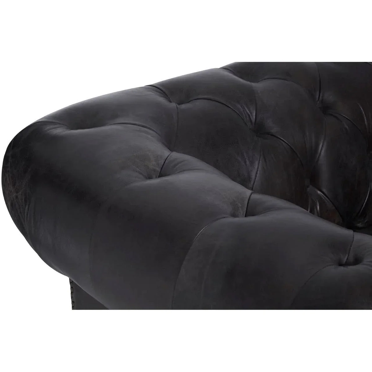 Close detail of black leather sofa arm with deep button tufting