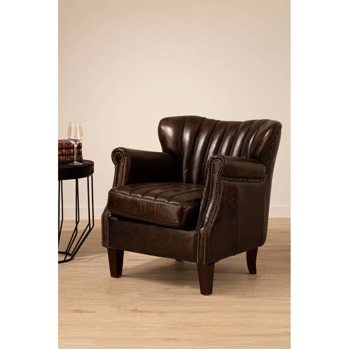 Dark brown leather armchair with studded arms and cushion, set on light wood flooring