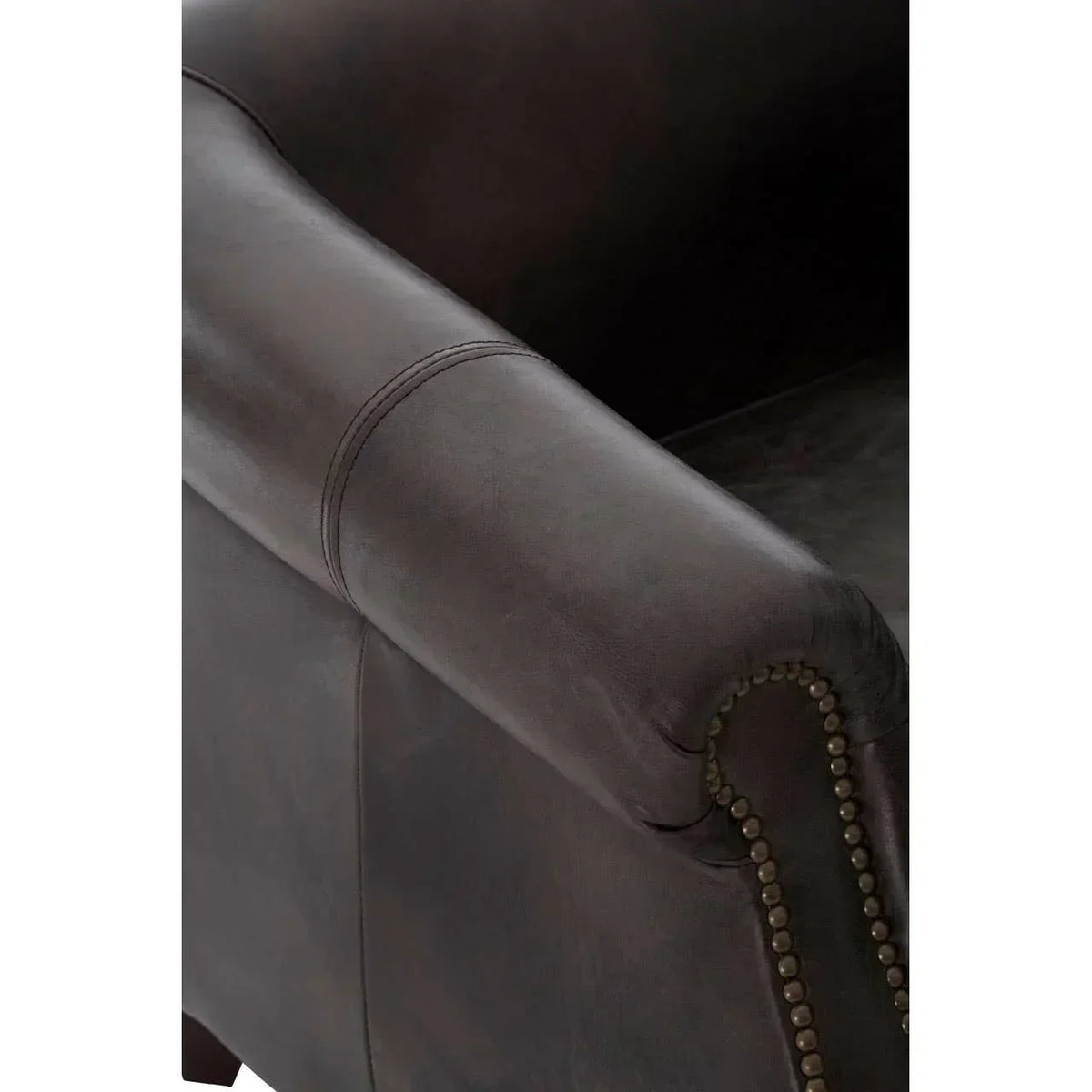 Close-up of brown leather sofa arm with brass nailhead trim