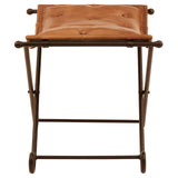 Buffalo brown leather folding stool with a cushioned seat and a sturdy iron frame, featuring a minimalist design and a natural finish. The stool is positioned upright, showcasing its compact and portable structure