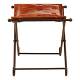 Buffalo tan leather folding stool with a smooth, curved seat and a sturdy iron frame, featuring a minimalist design and a compact, foldable structure for easy storage