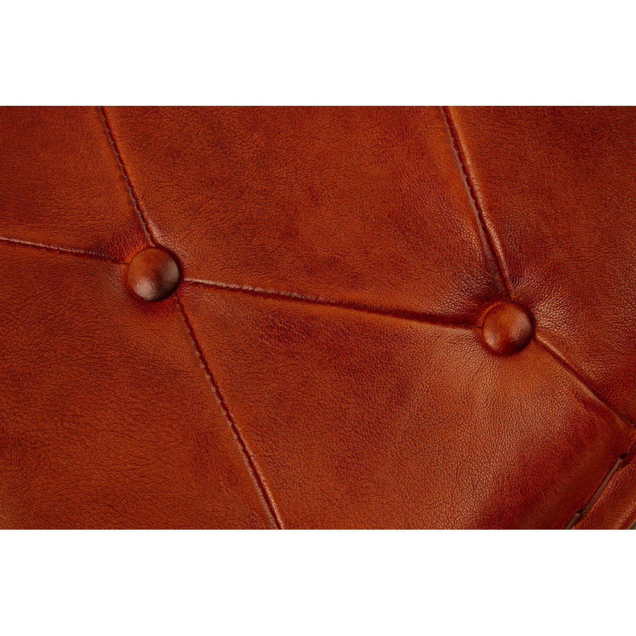 Close-up view of a buffalo tan leather folding stool featuring a tufted design with visible stitching and button accents, showcasing the rich texture and color of the leather