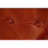 Close-up view of a buffalo tan leather folding stool featuring a tufted design with visible stitching and button accents, showcasing the rich texture and color of the leather