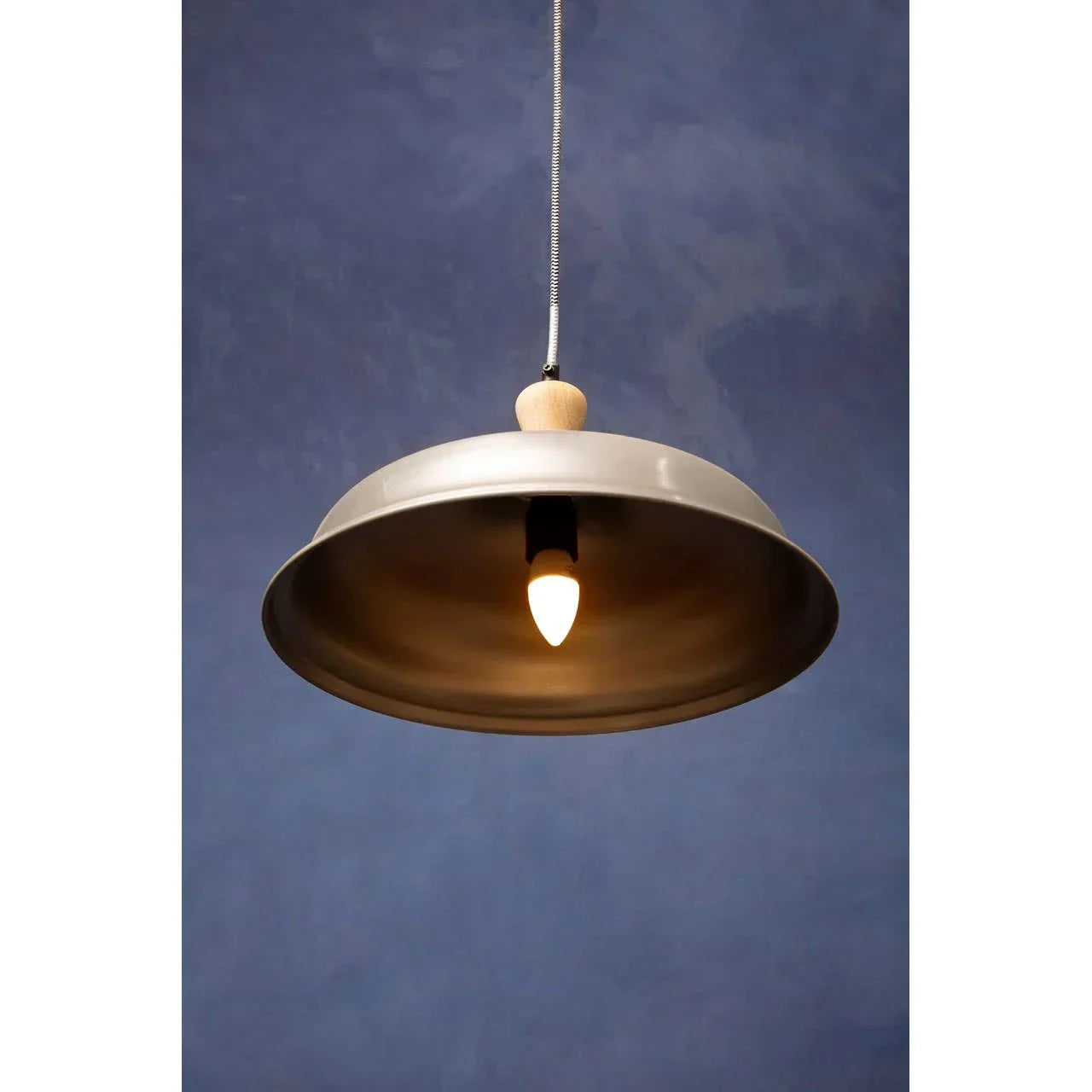 Silver metal pendant ceiling light with exposed bulb against blue wall