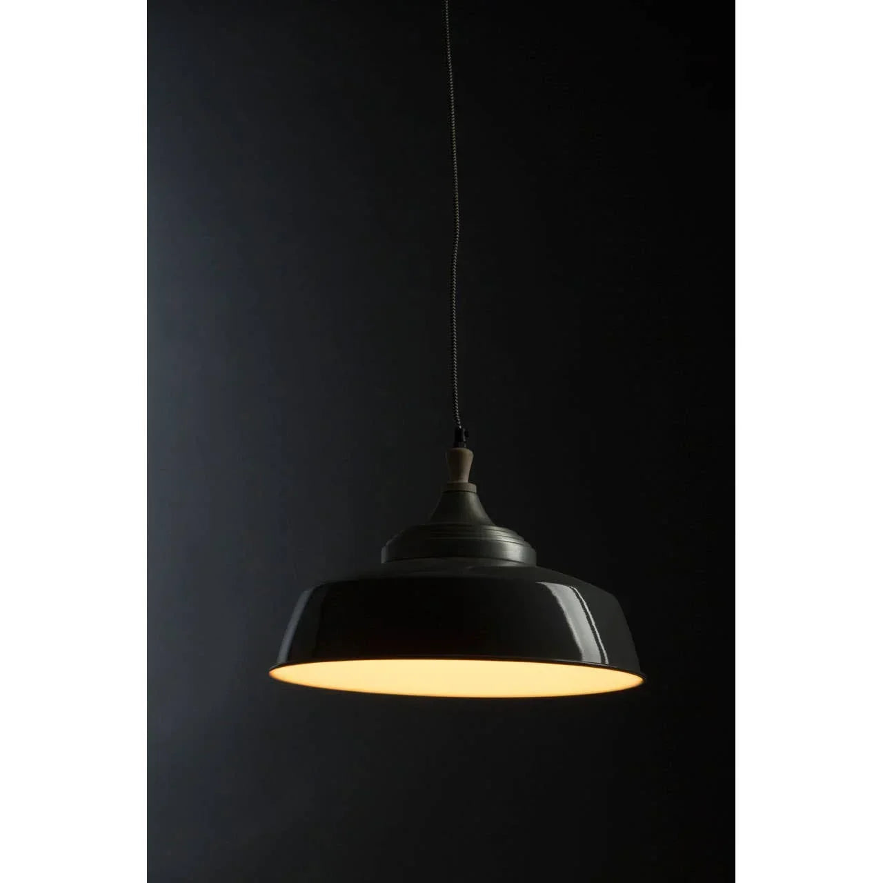 Black metal pendant ceiling light with warm glow against dark background