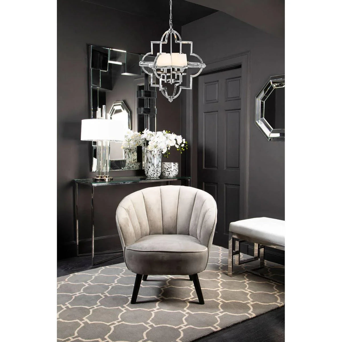 Grey velvet accent chair on patterned rug in modern hallway with console table and mirror