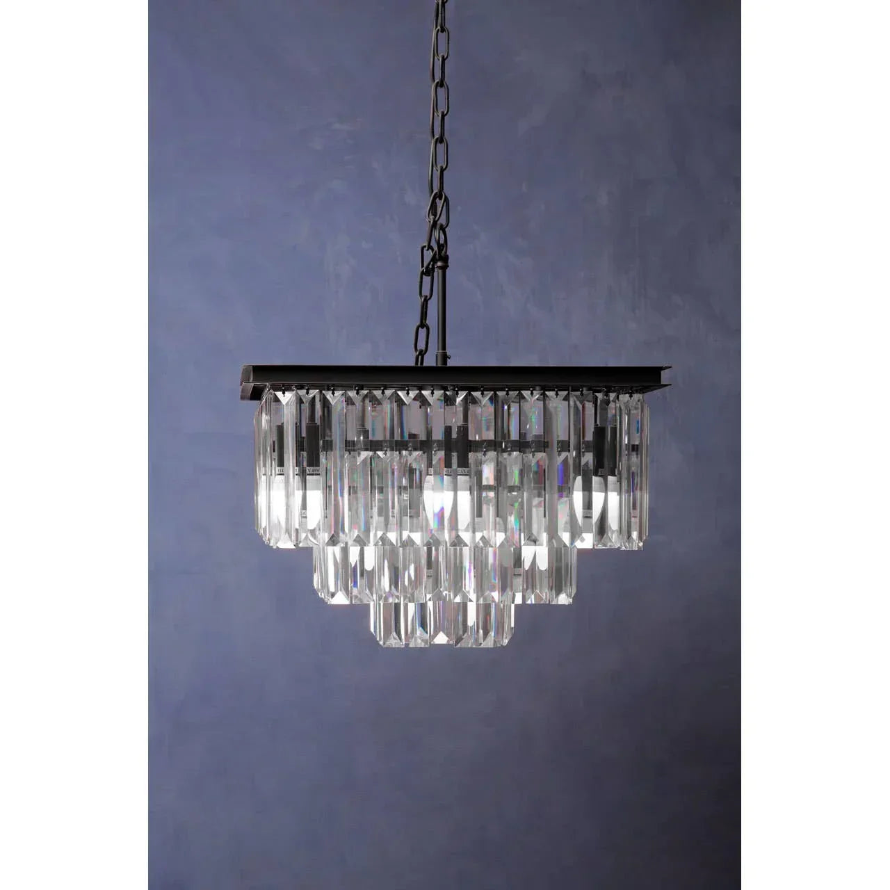 Rectangular crystal chandelier with chrome frame and tiered glass prisms against blue wall